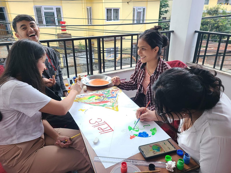 A group of people from Nepal sitting around a table playing with paint on the International Day of Peace.