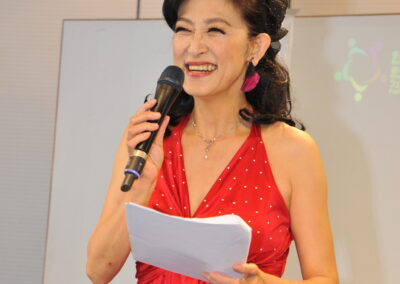A woman in a red dress captivating the audience with her powerful voice at the Multicultural One Family Festival 2023, while confidently holding a microphone.