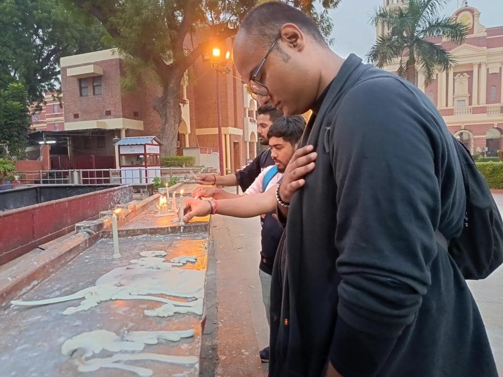 Interfaith Leadership promotes the unity of different facets of faith as a group of people light candles in front of a building.