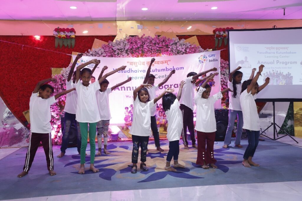 A group of children in white shirts performing on stage during the S.M.I.L.E Annual Day.