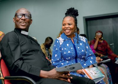 In Nigeria, a man and a woman are sitting in front of a group of people, deepening democracy through their engaging discussions and presentations.