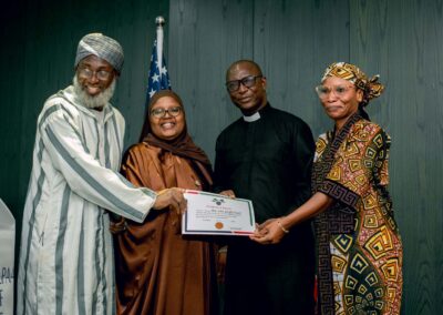 A group of people holding a certificate in front of the Nigerian flag.