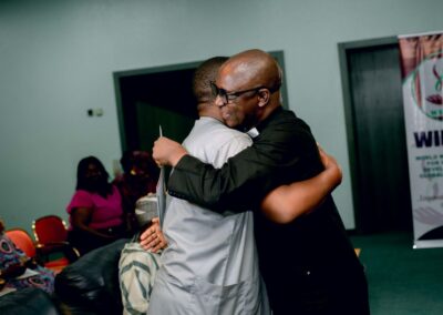 Two men are deepening democracy through a warm embrace at an event in Nigeria.