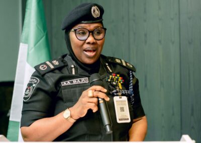 A female police officer from Nigeria is speaking into a microphone, promoting the deepening democracy efforts in the country.