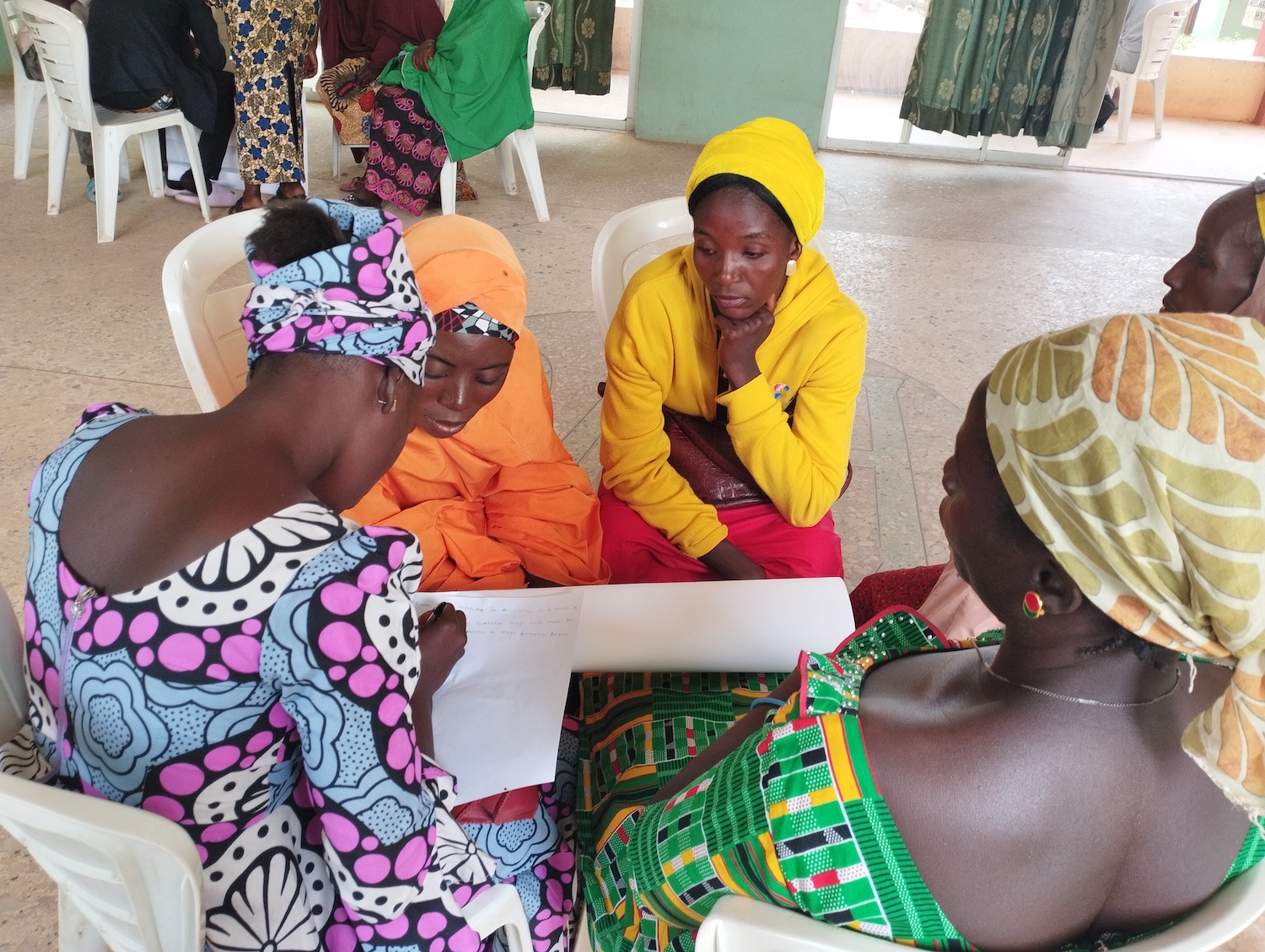 A group of women in Nigeria sitting around a table, commemorating Human Rights Day.
