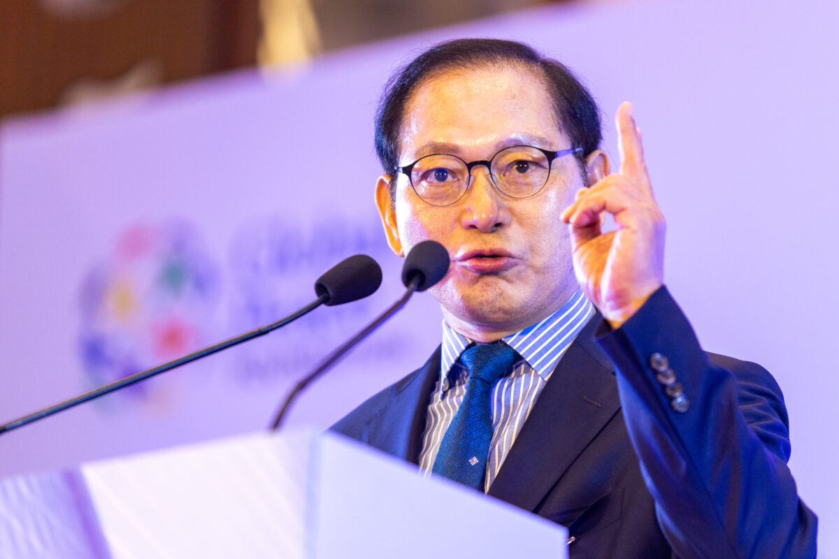 A man in a suit and tie giving a speech at an international forum on the economic prospects of reunification for one Korea.