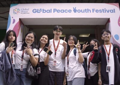 A group of people posing in front of a sign that says global peace youth festival.