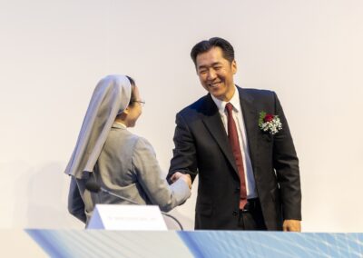 Dr. Hyun Jin Preston Moon and Sr. Merceditas Ang, SPC shaking hands during the Main Plenary of Global Peace Convention 2023