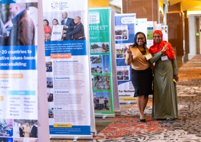 Project leaders from Global Peace Women Nigeria and Tanzania next to the GPF field affiliate's project banners