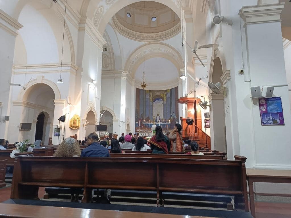 The interior of a church in India with people sitting in the pews.
