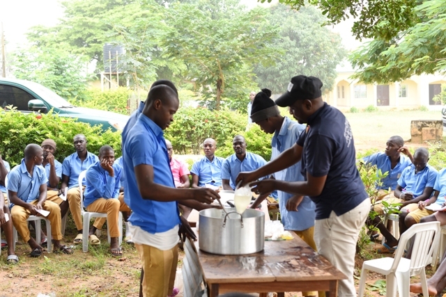 Youth in Nigeria participating in a skills acquisition training program gather around a table, learning how to prepare food.