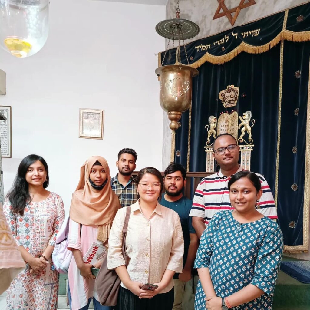 Facets of Faith promoting interfaith leadership in India, with a group of people standing in front of a Jewish temple.