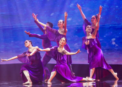 A group of dancers in beautiful purple dresses captivating the stage at an Awards Gala.