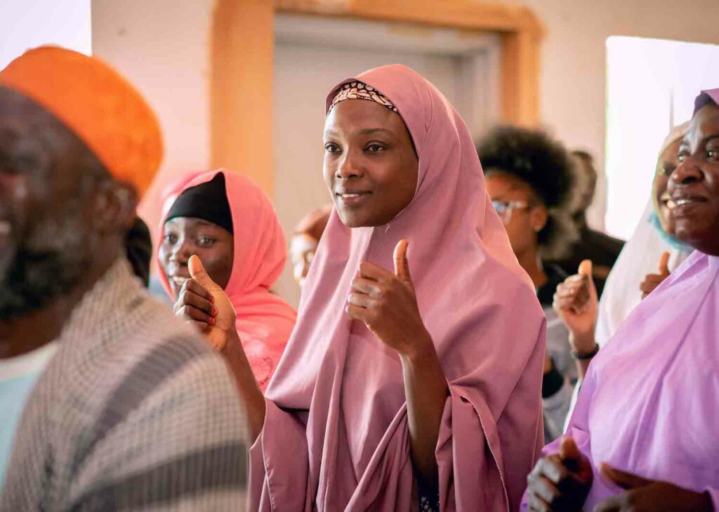 A woman in a pink hijab is giving a thumbs up, symbolizing freedom of religion.