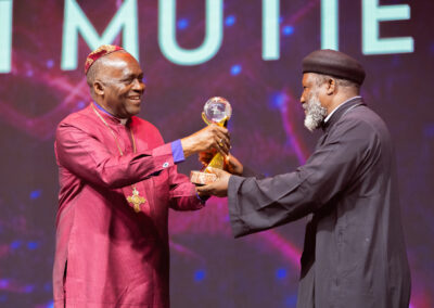 At a global convention, a man dressed in a robe is graciously presenting an award for peace to another individual.