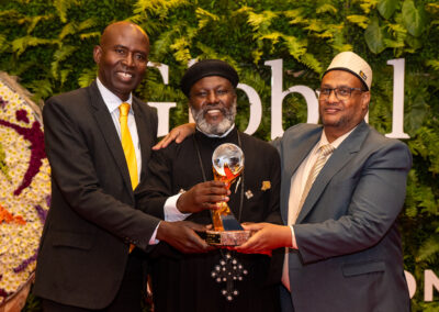 Three men posing with an award at the Global Peace Convention.