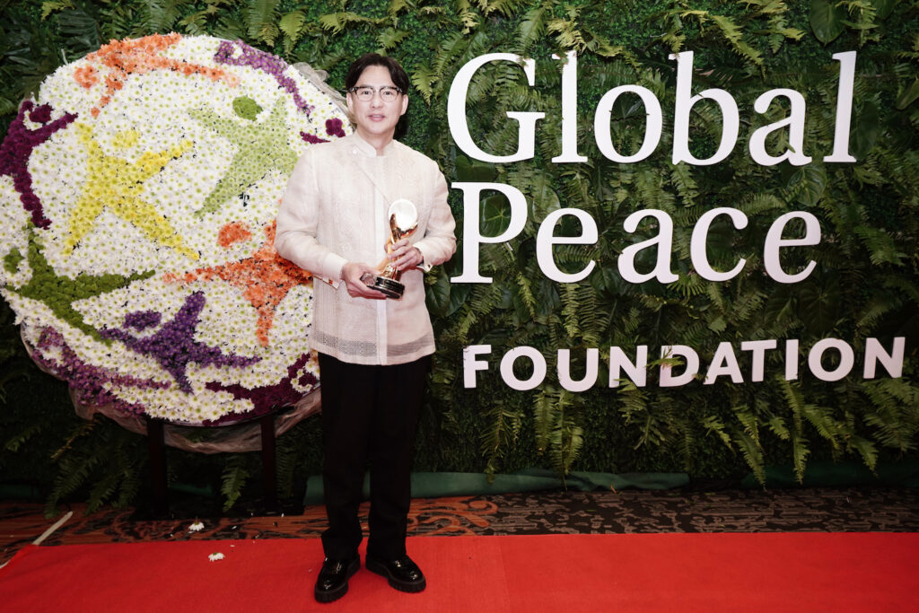 A man standing in front of a red carpet at the Global Peace Convention Awards Gala.