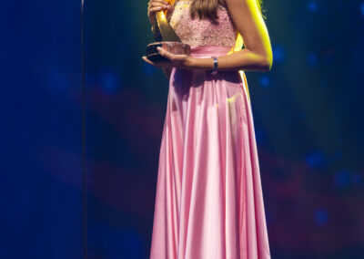 A woman in a pink dress receiving an award at the Awards Gala.