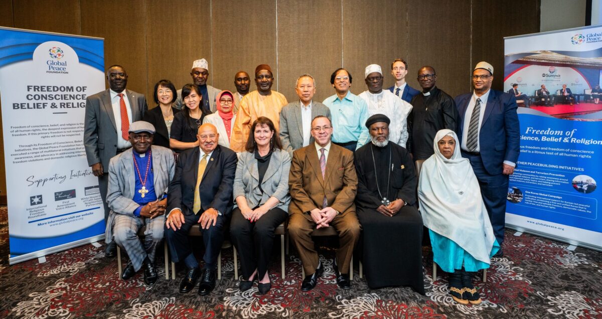 Religious freedom roundtable participants posing for a photo in front of a banner.