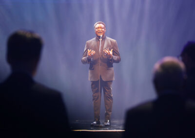 A man in a suit standing on a stage at the Global Peace Convention Awards Gala.
