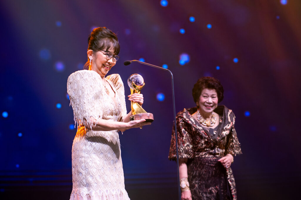 A woman holding an award on stage at the Awards Gala.