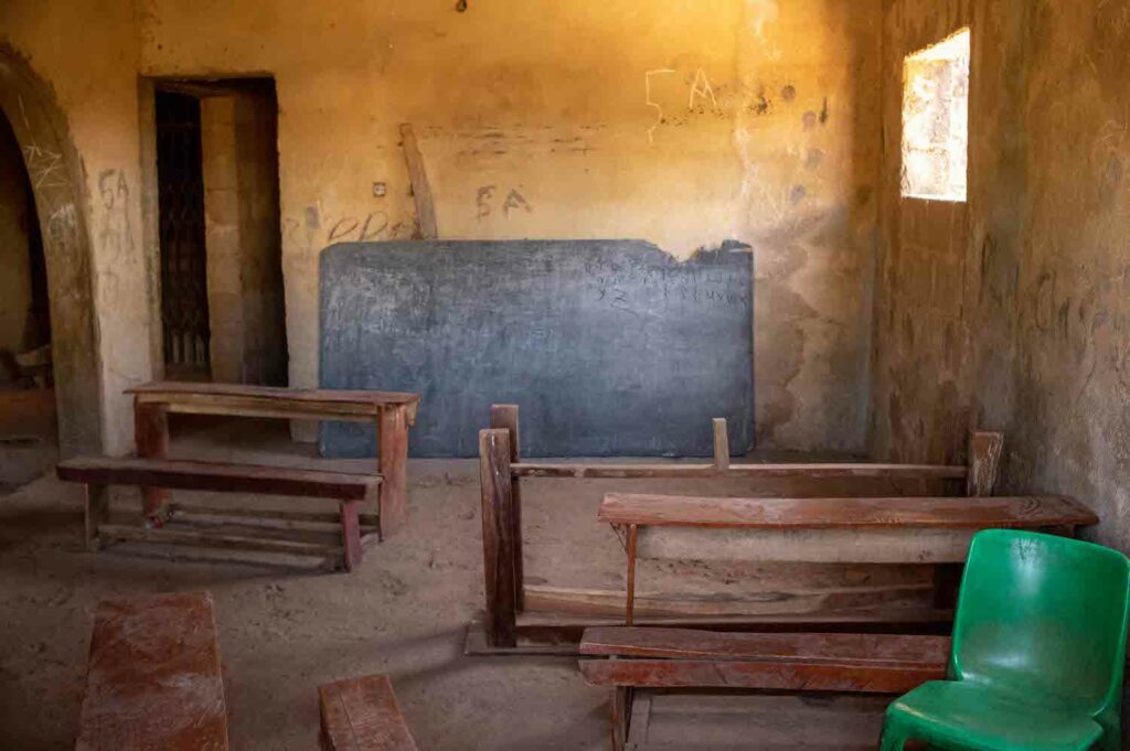 An empty classroom with Bukuru green chairs and a chalkboard.