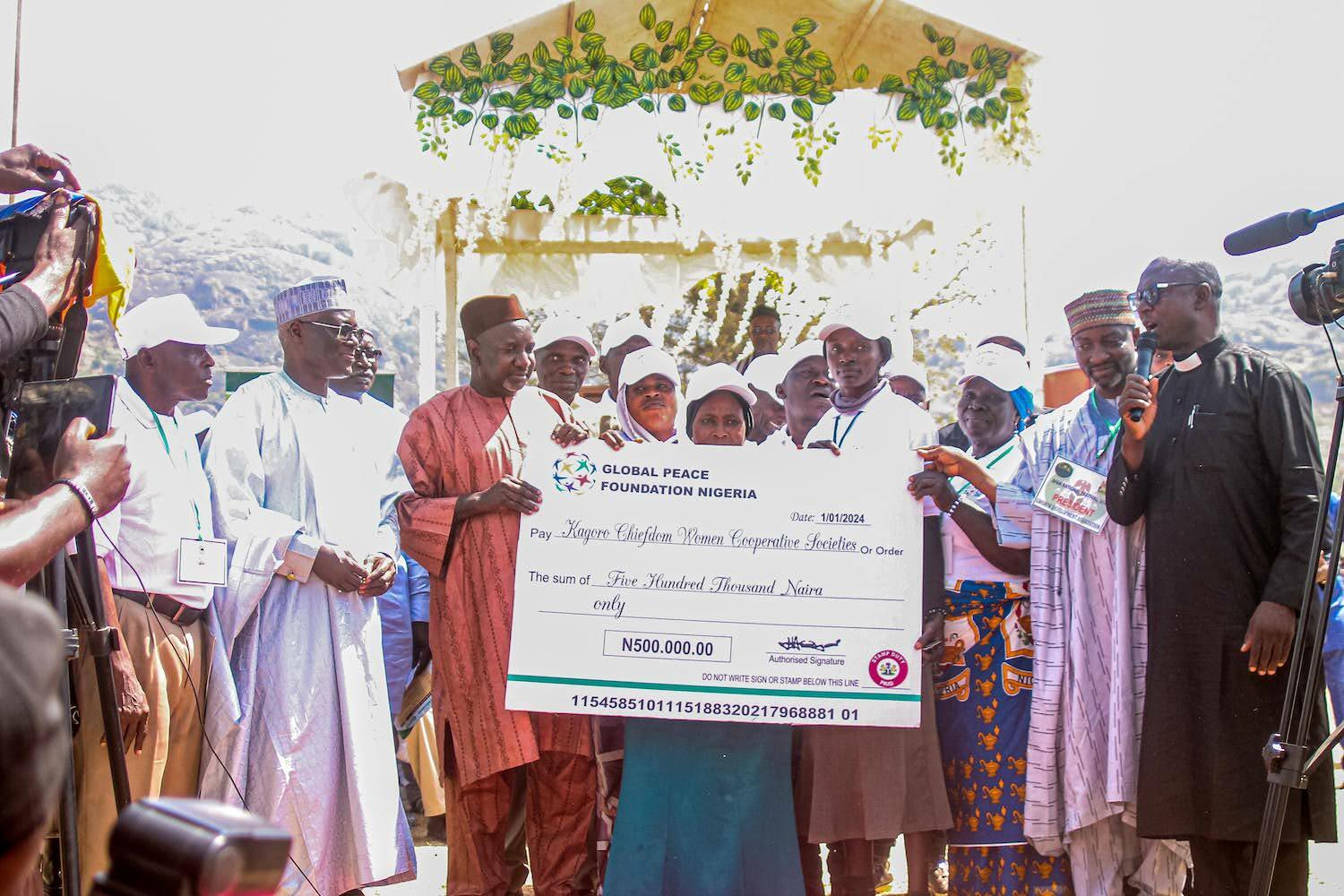 A group of people participating in the Afan Festival in Nigeria, come together to hold a check in front of a camera as a symbol of community peace.