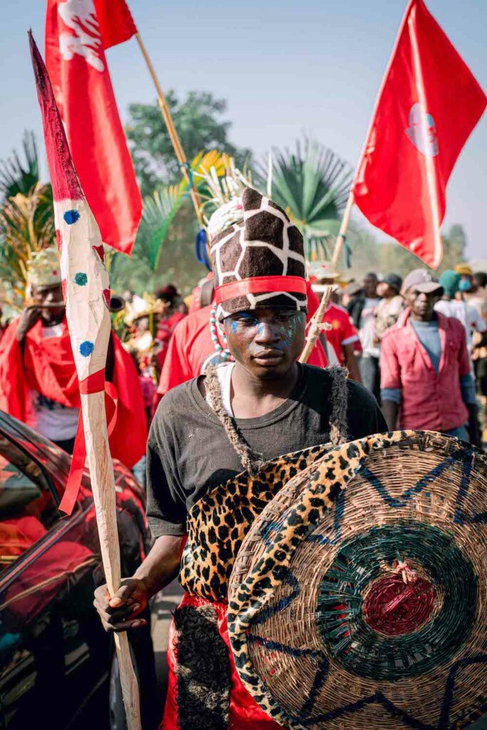 A man in a red costume holding a shield represents the spirit of Afan Festival in Nigeria, fostering community peace and unity.