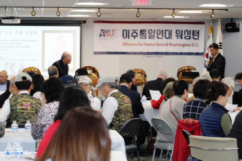 Gathering of individuals at a forum hosted by the Alliance for Korea United in Washington D.C., with a speaker addressing the audience.