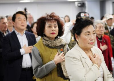 Group of individuals standing with hands over hearts during a formal event organized by the Alliance for Korea United.