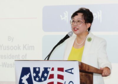 A woman speaking at a forum with the United States and South Korean flags displayed, commemorating the March 1 Movement.