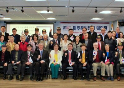 Group of people posing for a photo at an event with South Korean flags commemorating the March 1 Movement in the background.