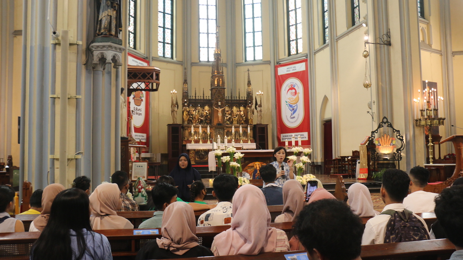 Visitors seated on benches inside Jakarta Cathedral Church with ornate interior design, listening to a woman speaking at the front as Peace!Project 2024 kicks off.