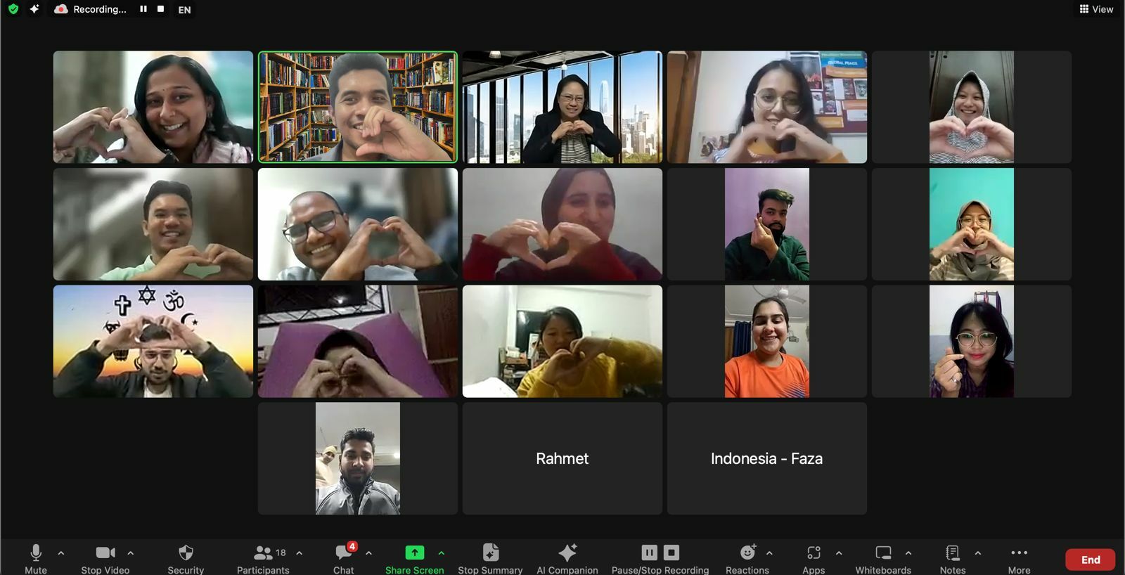 A group of individuals from a Youth Interfaith meeting participating in a video call, making heart shapes with their hands.
