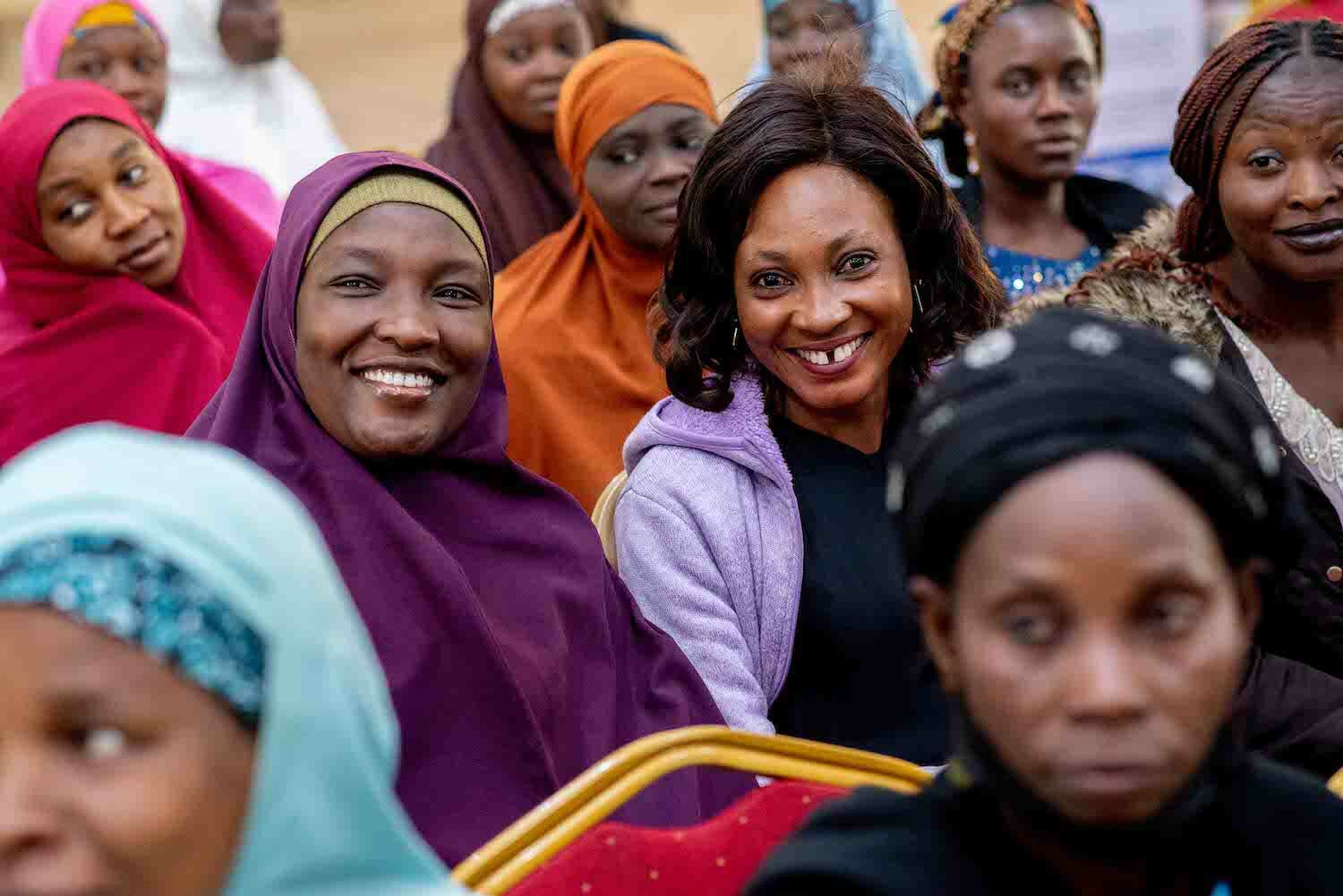 A group of Nigerian women with diverse facial expressions sitting together while two in the foreground smile at the camera after a Financial Literacy Training session.