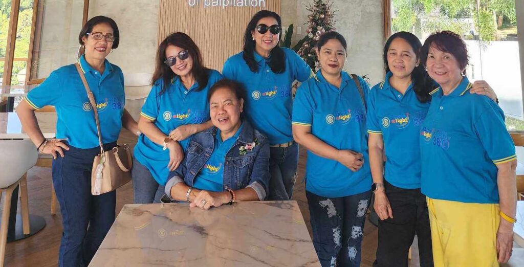 A group of women from the Inner Wheel Club of Central Ortigas, wearing matching blue polos with a logo, posing together for a photo in a lobby area.