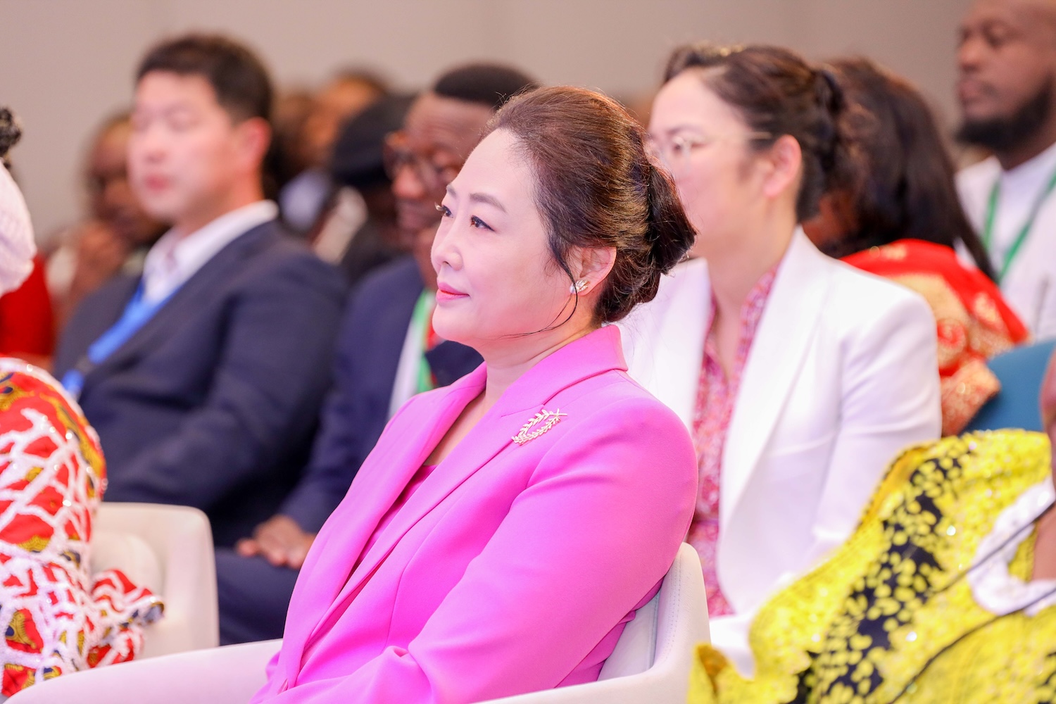 A woman in a pink blazer sits among other attendees at what appears to be the Family Track session of GPLC Africa 2024, a formal event or conference.