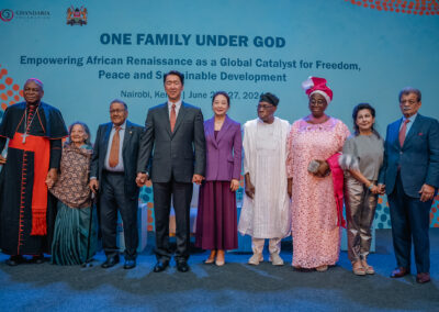 A group of eight people, including dignitaries and leaders, stand together on a stage at the "One Family Under God" event in Nairobi, Kenya. The backdrop highlights themes of freedom, peace, and sustainable development, setting the tone for the upcoming GPLC Africa 2024 plenary.
