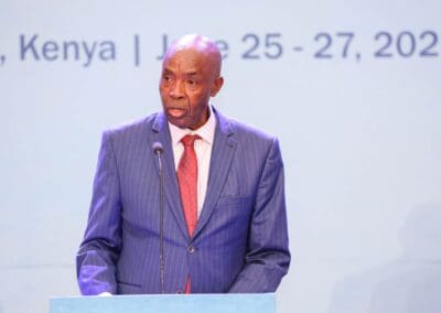 A man in a pinstripe suit and red tie speaks at a podium. The background displays text indicating the GPLC Africa 2024 event in Nairobi, Kenya from June 25-27, 2024, with a focus on the education track.