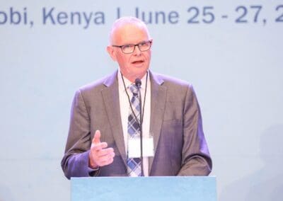 Man in a grey suit and patterned tie speaking at a podium with a microphone. Text in the background indicates an event in Nairobi, Kenya, from June 25-27, 2024. This session is part of the GPLC Africa's Education Track.