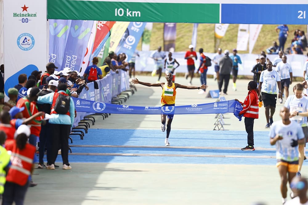 At the Standard Chartered Nairobi Marathon, a runner crosses the finish line with arms outstretched, surrounded by cheering spectators and race officials—thanks to partners like GPF Kenya for making this moment unforgettable.