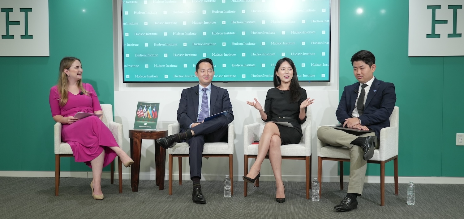 Four young leaders sit on stage in Washington, engaging in a lively discussion. One woman gestures animatedly while speaking, with a logo prominently displayed in the background.