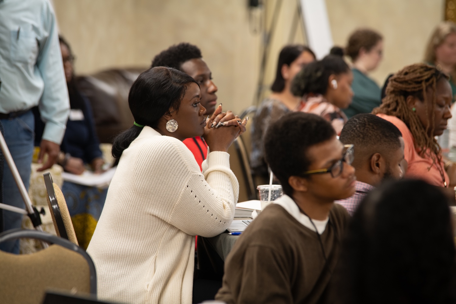 People seated in a conference room attentively listen during a meeting focused on fostering community resilience and creating safer schools.