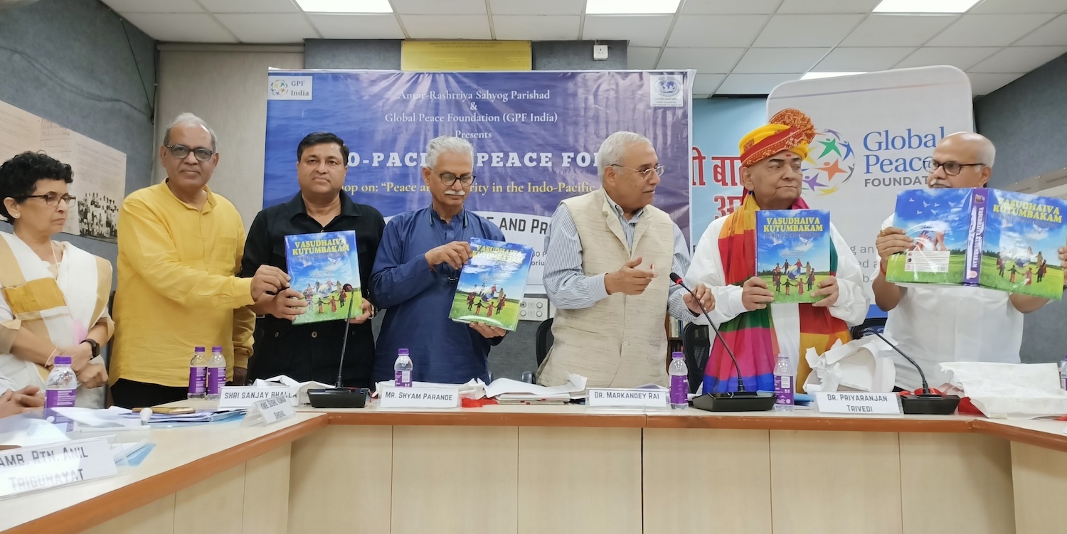 A group of people stands together holding a book titled "Interfaith Harmony and Peace." They are gathered in a room with a banner that says "Global Peace Foundation." The gathering highlights GPF India's commitment to fostering peace and security across the Indo-Pacific region.