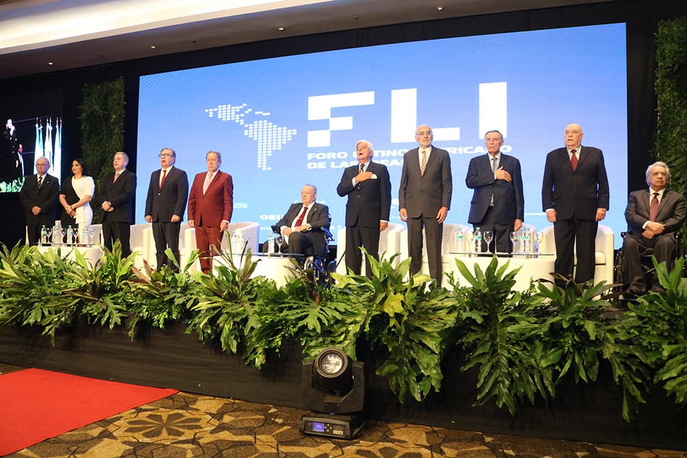A group of officials stands on stage in front of a logo reading