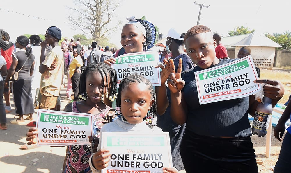 Amidst the vibrant crowd at the AFAN Festival, a group of people outdoors hold signs reading