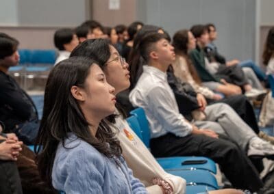 Audience seated in a room, attentively watching a presentation or event.