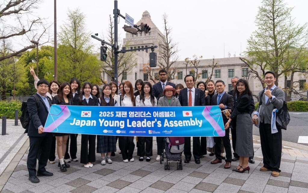 A group of youth leaders and adults pose outdoors holding a banner that reads