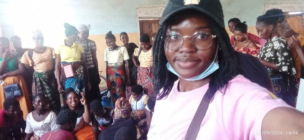 A woman takes a selfie in a room with a group of people, most of whom are women standing and sitting together, highlighting strong family ties. The timestamp shows 21/09/2024 14:04.