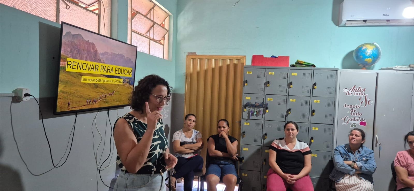 A woman speaks to a seated group in a classroom; behind her, a screen displays “Renovar para educar” in Portuguese, highlighting GPF Brazil’s commitment to youth empowerment and peacebuilding.